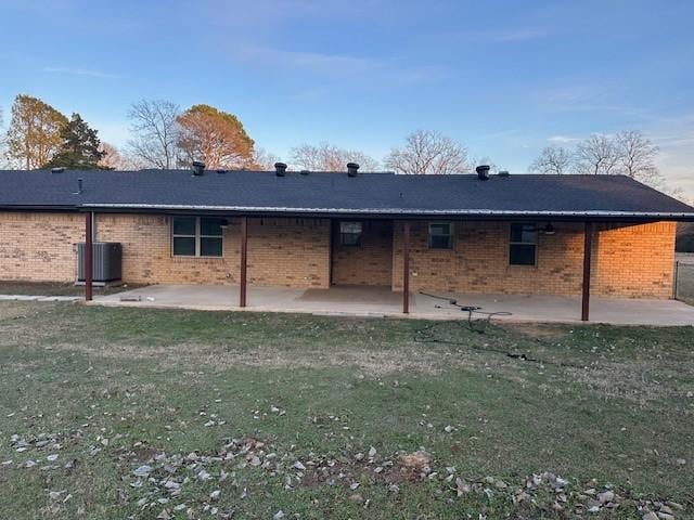 back of property featuring a lawn, central air condition unit, and a patio