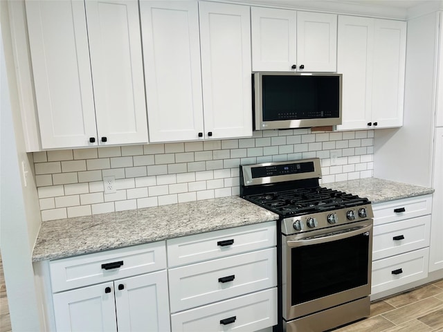 kitchen with appliances with stainless steel finishes, decorative backsplash, white cabinetry, and light stone countertops