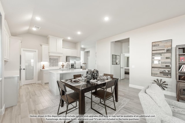 dining area with sink, light hardwood / wood-style floors, and lofted ceiling