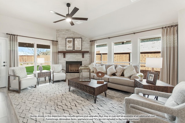 living room featuring a fireplace, light hardwood / wood-style flooring, ceiling fan, and lofted ceiling