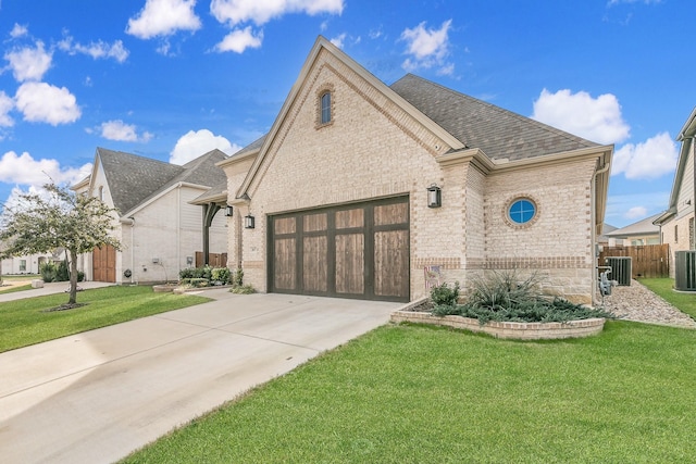 view of front facade featuring a garage, a front lawn, and central air condition unit