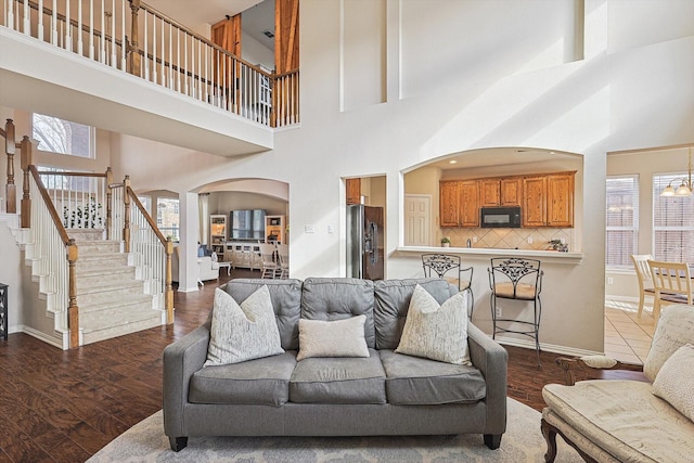 living room with dark hardwood / wood-style flooring, a high ceiling, and an inviting chandelier