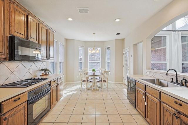 kitchen featuring sink, an inviting chandelier, pendant lighting, light tile patterned floors, and black appliances