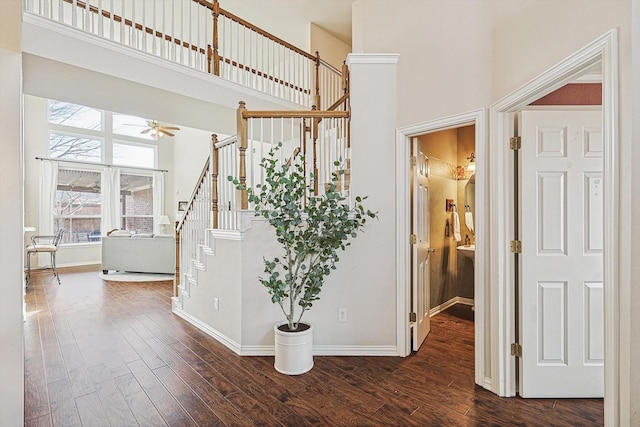 staircase with hardwood / wood-style flooring, ceiling fan, and a towering ceiling