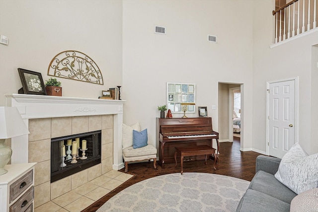 living room with wood-type flooring, a fireplace, and a high ceiling