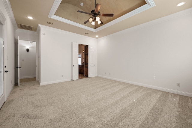 unfurnished bedroom with connected bathroom, crown molding, light carpet, a tray ceiling, and ceiling fan