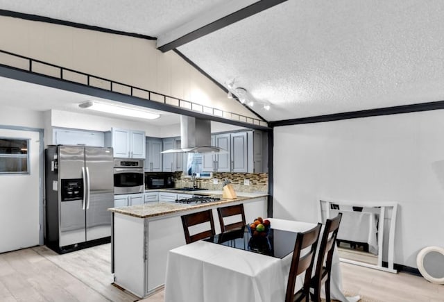 kitchen with wall chimney range hood, kitchen peninsula, decorative backsplash, appliances with stainless steel finishes, and light wood-type flooring