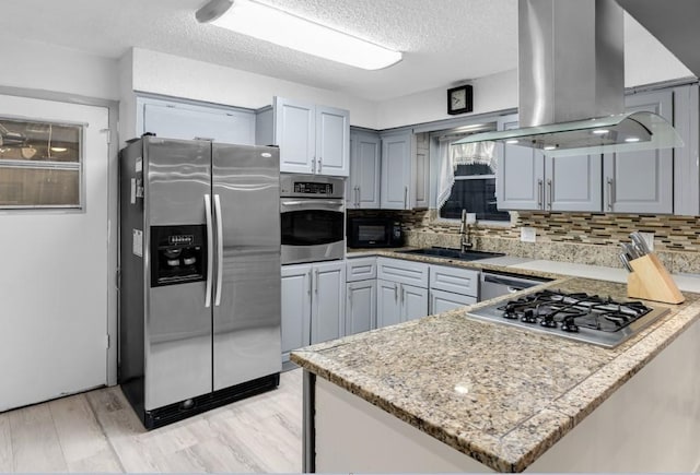 kitchen featuring sink, kitchen peninsula, island exhaust hood, and appliances with stainless steel finishes