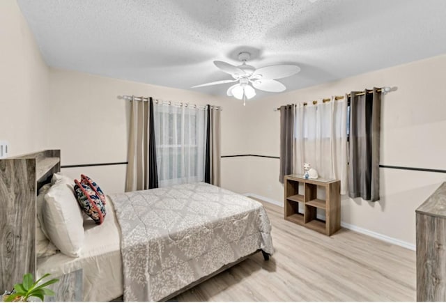 bedroom featuring ceiling fan, a textured ceiling, and light hardwood / wood-style flooring