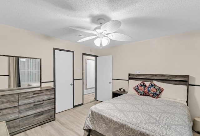 bedroom with ceiling fan, light hardwood / wood-style floors, and a textured ceiling