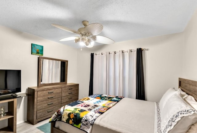 bedroom featuring ceiling fan, light hardwood / wood-style floors, and a textured ceiling