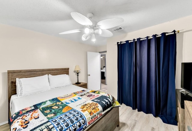 bedroom featuring ceiling fan, light wood-type flooring, and a textured ceiling