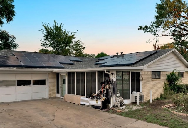 ranch-style home with a sunroom, a garage, and solar panels