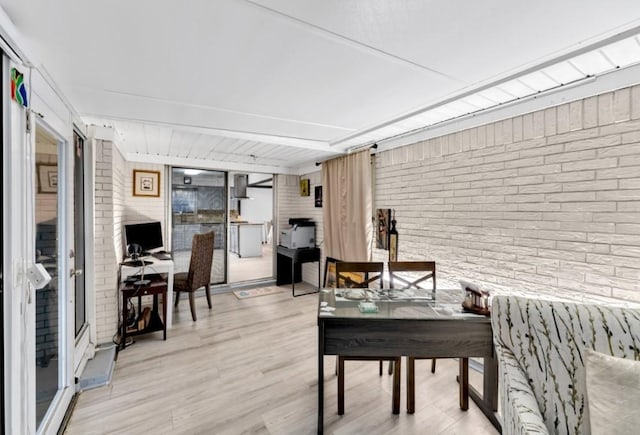 home office featuring brick wall and light wood-type flooring