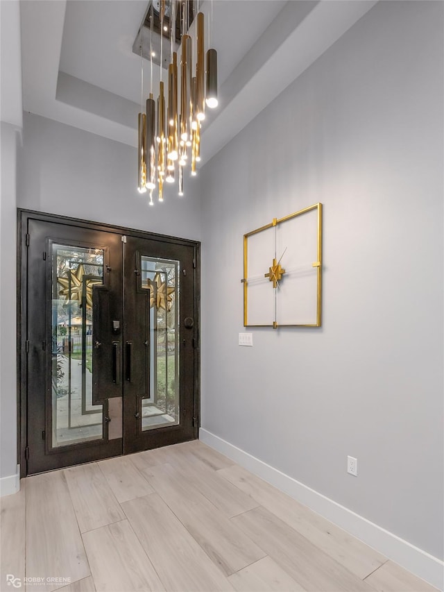 interior space featuring a tray ceiling, french doors, and a notable chandelier