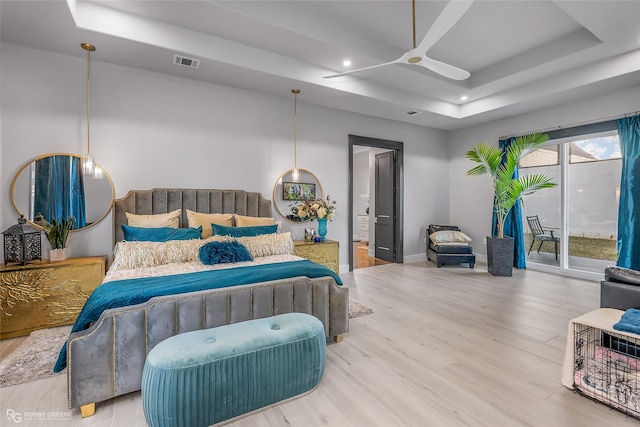 bedroom with hardwood / wood-style floors, ceiling fan, a raised ceiling, and access to outside