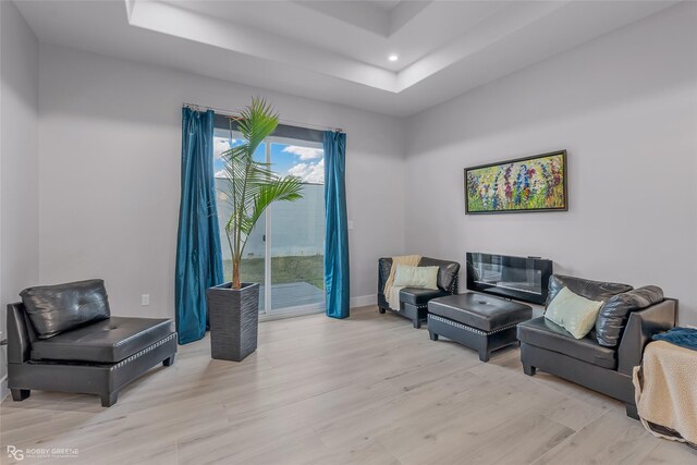 living room featuring light hardwood / wood-style floors and a tray ceiling