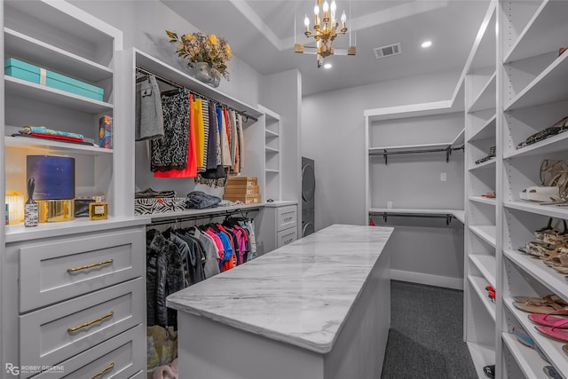 spacious closet featuring an inviting chandelier and dark carpet