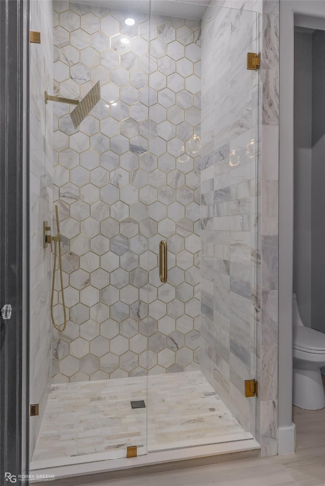 bathroom with a shower with shower door and toilet