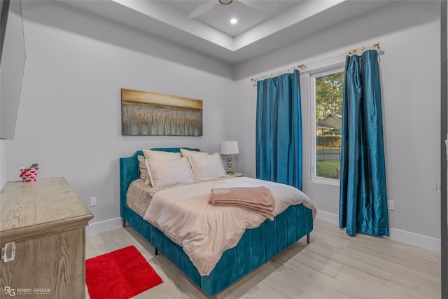 bedroom with a raised ceiling, ceiling fan, and hardwood / wood-style flooring