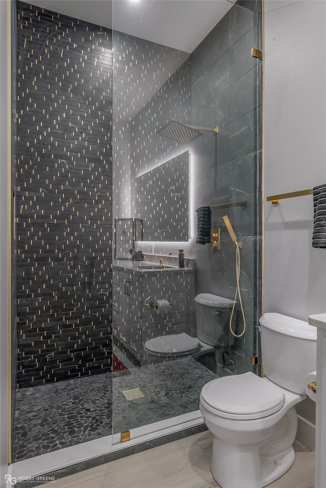 bathroom with a tile shower and toilet