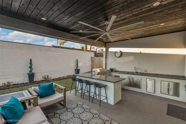 view of patio / terrace with an outdoor living space, grilling area, an outdoor kitchen, ceiling fan, and a wet bar