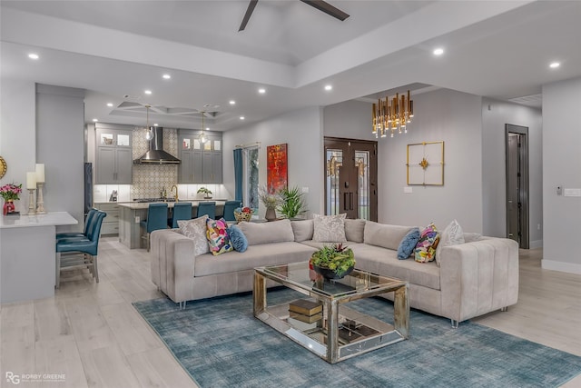 living room featuring french doors, ceiling fan, a tray ceiling, and light hardwood / wood-style flooring