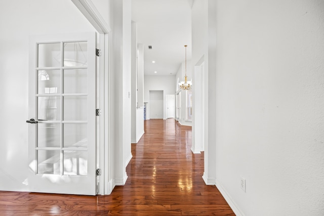 hallway with dark hardwood / wood-style floors and a chandelier