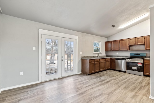 kitchen featuring a wealth of natural light, vaulted ceiling, appliances with stainless steel finishes, and french doors