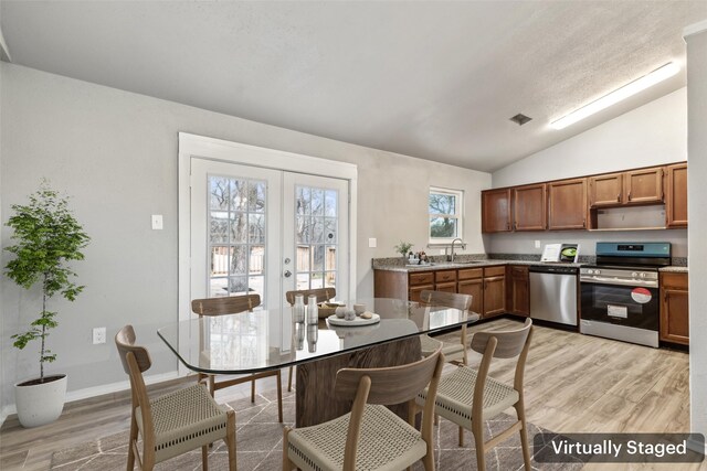 kitchen featuring sink, french doors, stainless steel appliances, light hardwood / wood-style flooring, and lofted ceiling