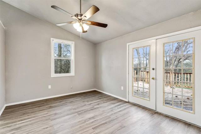 empty room with ceiling fan, french doors, lofted ceiling, and light wood-type flooring