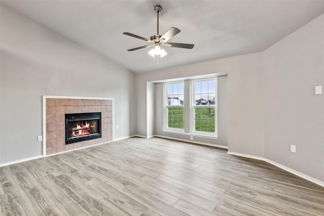 unfurnished living room with light hardwood / wood-style flooring, ceiling fan, lofted ceiling, and a tiled fireplace