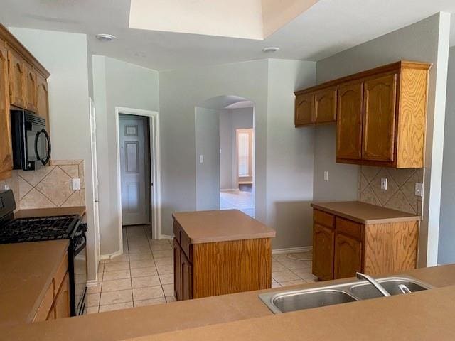 kitchen with a center island, black appliances, sink, decorative backsplash, and light tile patterned flooring