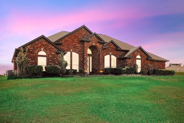 view of front of house featuring cooling unit and a lawn