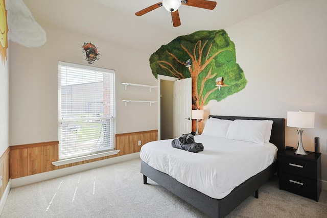 carpeted bedroom with ceiling fan and wood walls