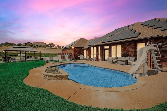 pool at dusk featuring a gazebo, a water slide, a lawn, an outdoor living space, and a patio