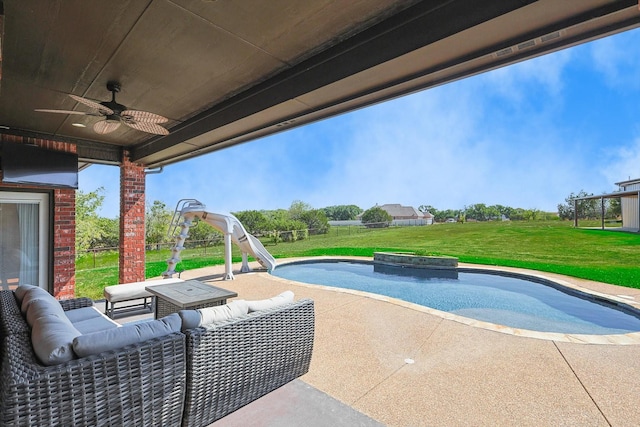 view of swimming pool with a lawn, outdoor lounge area, a water slide, ceiling fan, and a patio area