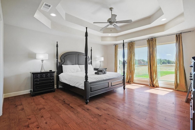 bedroom featuring dark hardwood / wood-style floors, ceiling fan, and a tray ceiling