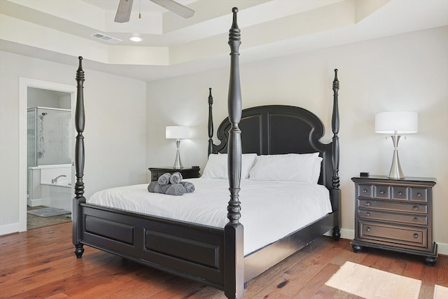 bedroom with dark hardwood / wood-style floors, ceiling fan, and a tray ceiling