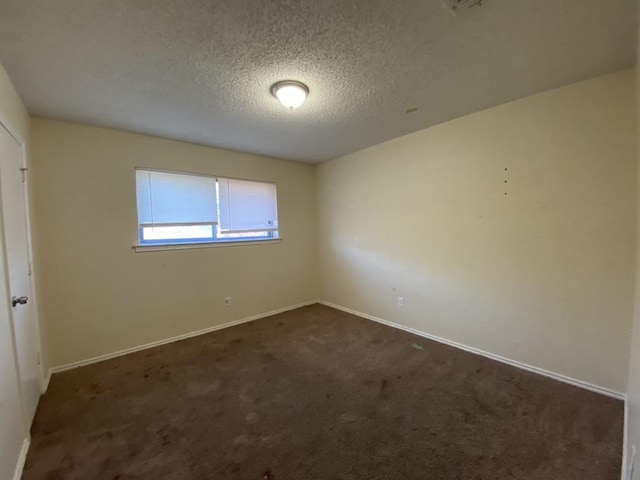 unfurnished room with dark colored carpet and a textured ceiling