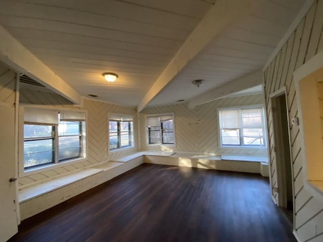 empty room with beamed ceiling, dark wood-type flooring, and wooden walls