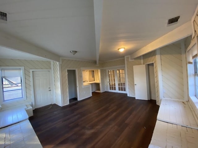 unfurnished living room with dark hardwood / wood-style floors, beam ceiling, and wooden walls