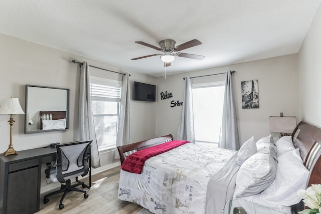 bedroom with a textured ceiling, light hardwood / wood-style flooring, and ceiling fan