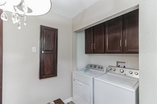 clothes washing area with a notable chandelier, cabinets, and independent washer and dryer