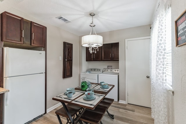 kitchen featuring light wood-type flooring, dark brown cabinets, pendant lighting, independent washer and dryer, and white fridge