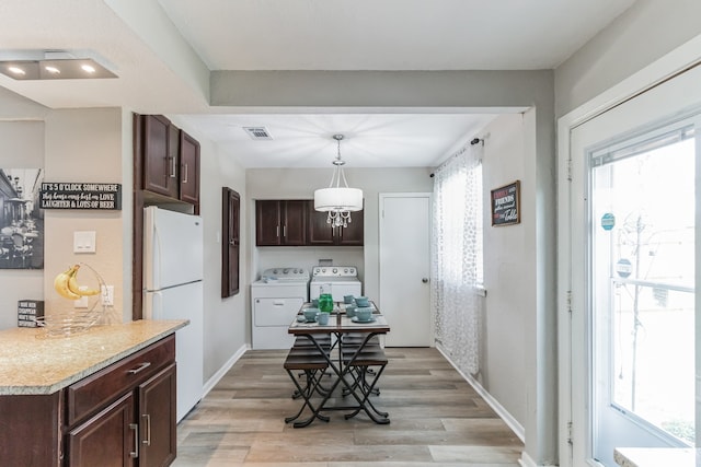 kitchen with independent washer and dryer, white fridge, light hardwood / wood-style floors, pendant lighting, and dark brown cabinets