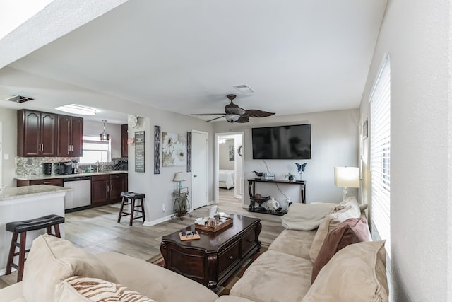 living room featuring ceiling fan, light hardwood / wood-style flooring, and sink