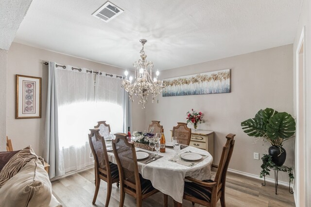 dining space with ceiling fan with notable chandelier and light wood-type flooring