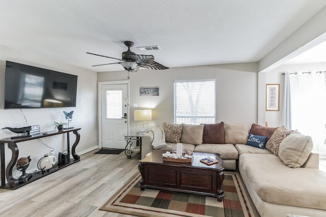 living room with ceiling fan, light hardwood / wood-style flooring, and a textured ceiling