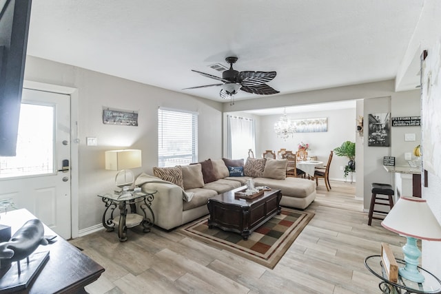 living room featuring light hardwood / wood-style floors and ceiling fan with notable chandelier